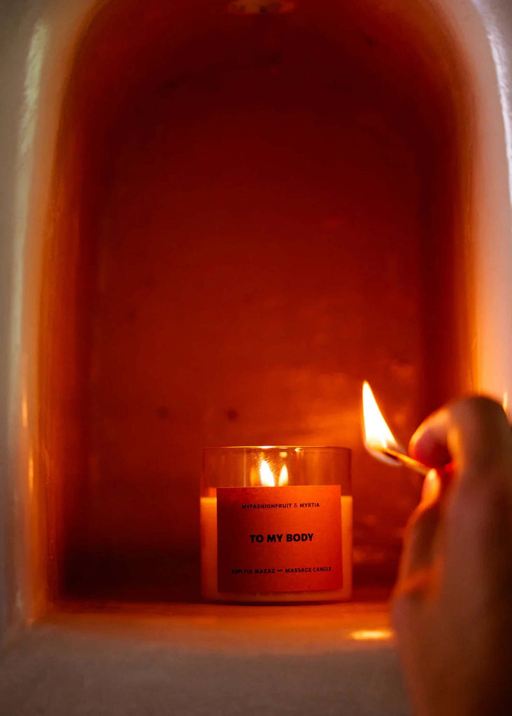 Massage Candle — Lit candle with orange label detail — MYFASHIONFRUIT