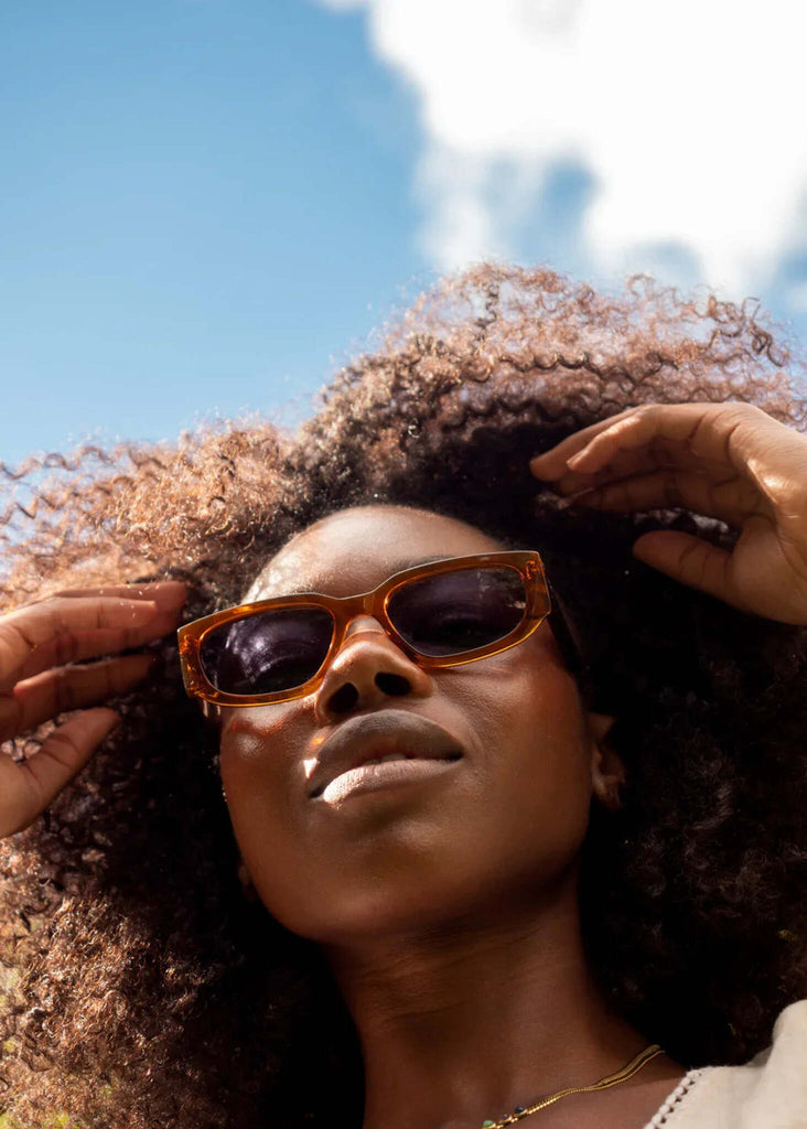 Woman wearing Komono REX Rust sunglasses against a blue sky — MYFASHIONFRUIT