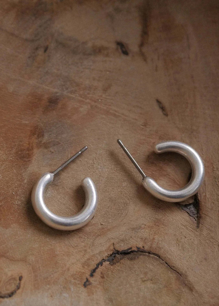 Nikki Hoops — Silver, c-shaped earrings on wood — MYFASHIONFRUIT